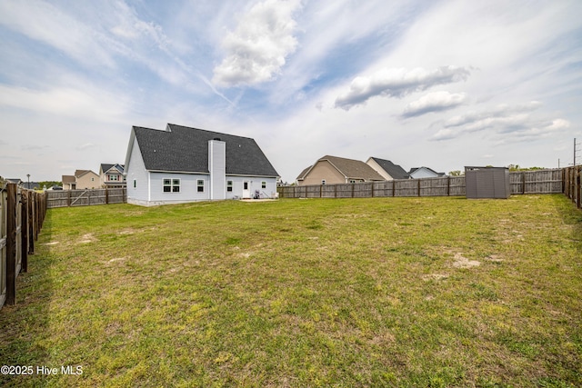 view of yard with a fenced backyard, an outbuilding, and a storage shed