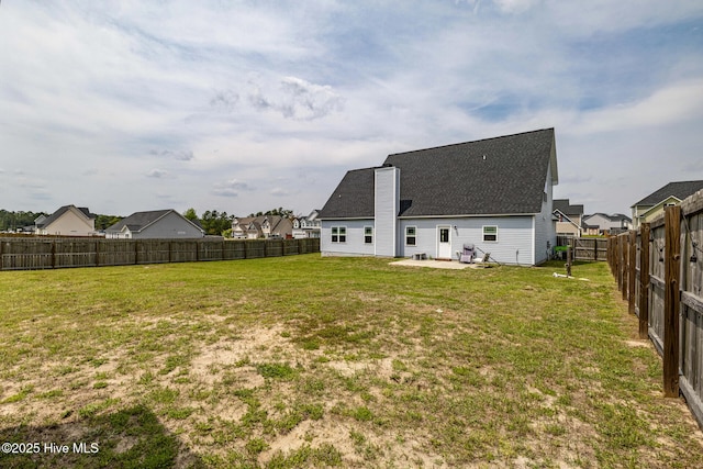 rear view of house featuring a lawn, a fenced backyard, a patio, and a shingled roof