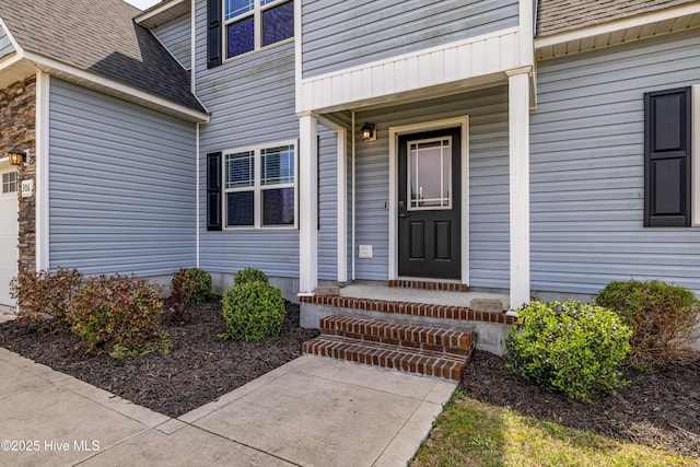 property entrance featuring an attached garage and a shingled roof