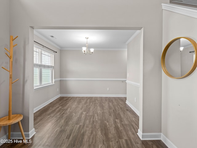 unfurnished room featuring an inviting chandelier, wood finished floors, ornamental molding, and baseboards