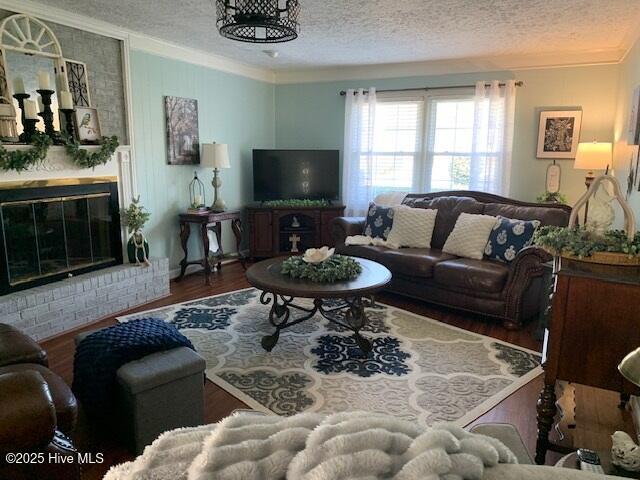 living room with crown molding, dark wood-type flooring, a fireplace, and a textured ceiling