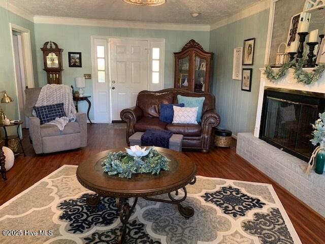 living room with dark hardwood / wood-style flooring, a fireplace, ornamental molding, and a textured ceiling