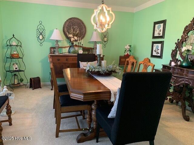 carpeted dining space with ornamental molding and an inviting chandelier