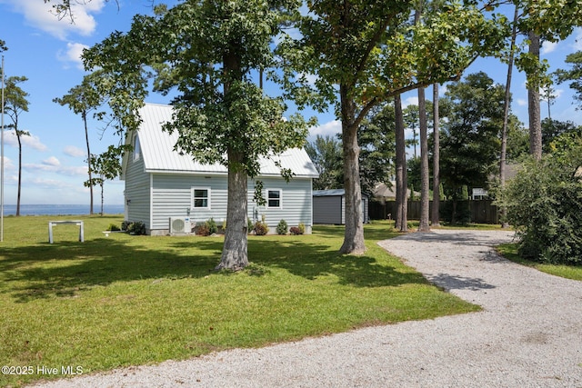 exterior space with metal roof, driveway, and a front lawn