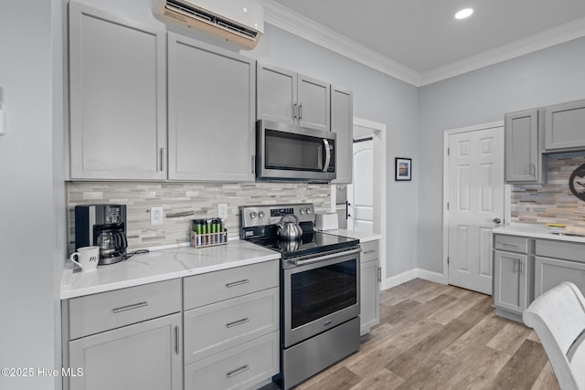 kitchen featuring gray cabinetry, appliances with stainless steel finishes, light wood-type flooring, a wall mounted air conditioner, and crown molding