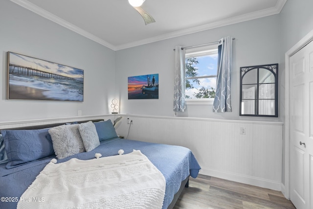 bedroom featuring ornamental molding, wainscoting, and wood finished floors