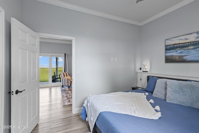 bedroom featuring baseboards, wood finished floors, and crown molding