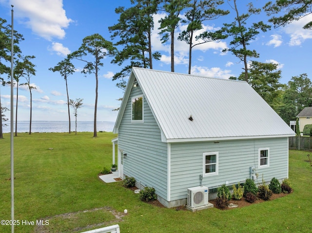 view of side of home featuring ac unit, metal roof, a water view, and a yard