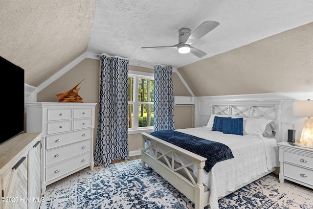 bedroom featuring a ceiling fan, vaulted ceiling, and a textured ceiling