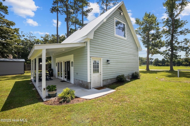 back of property featuring metal roof, a yard, french doors, and a patio