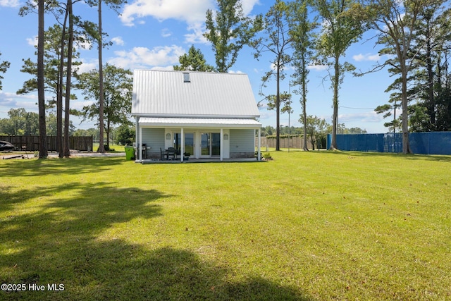 back of property with metal roof, a yard, and a fenced backyard