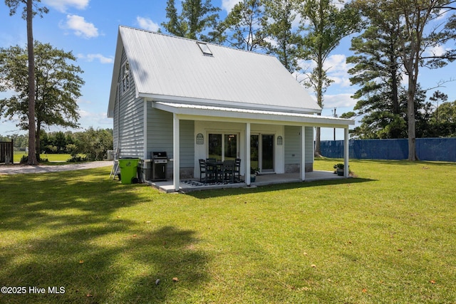 rear view of house with metal roof, a patio, a lawn, and fence