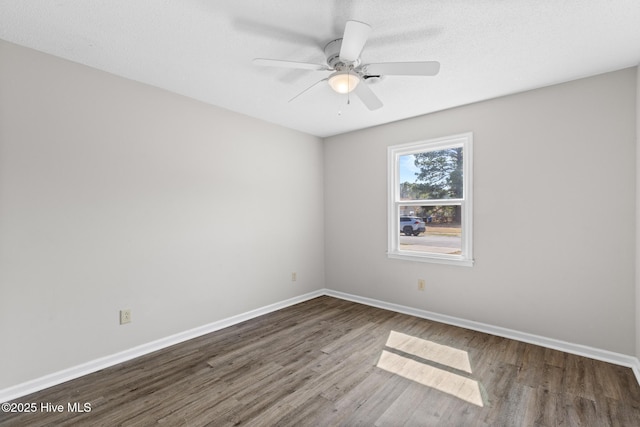 spare room featuring ceiling fan, baseboards, and wood finished floors