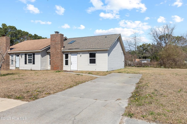 ranch-style home featuring a chimney, a front lawn, and a shingled roof