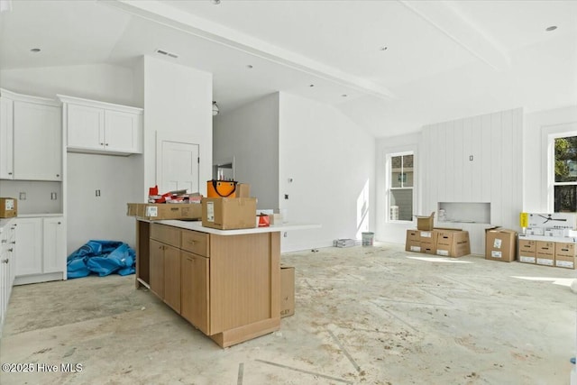 kitchen featuring a kitchen island, white cabinets, and vaulted ceiling with beams