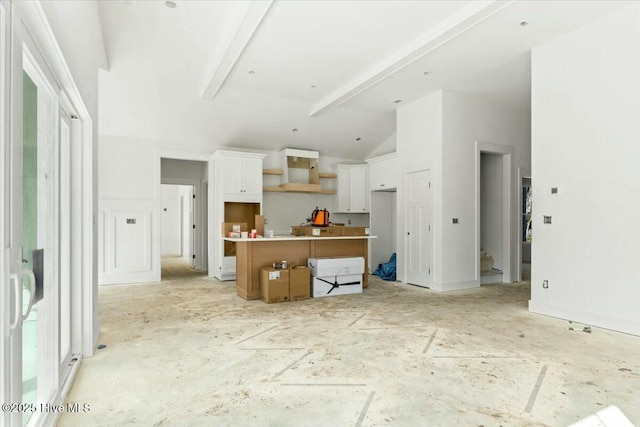 kitchen with a kitchen island, white cabinets, vaulted ceiling with beams, and wall chimney exhaust hood