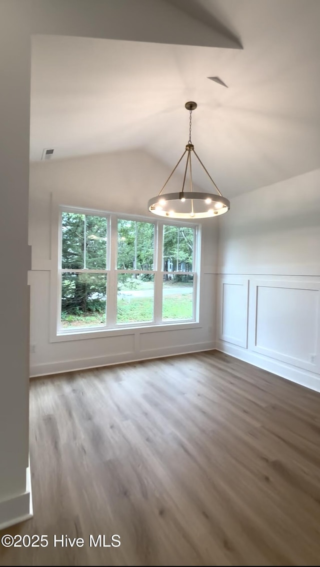 1643 Deerfield Dr SW, Ocean Isle Beach, NC 28469 - unfurnished dining area with a chandelier, healthy amount of natural light, wood finished floors, lofted ceiling, and a wainscoted wall