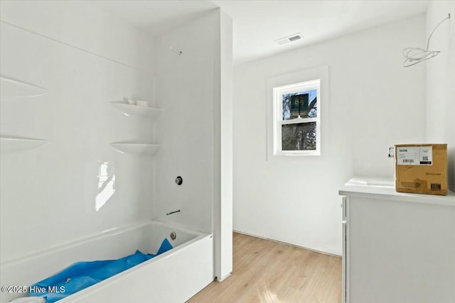 bathroom with bathtub / shower combination, vanity, and hardwood / wood-style floors