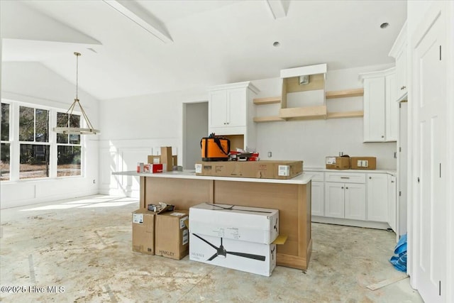 kitchen with lofted ceiling, white cabinets, a center island, and pendant lighting