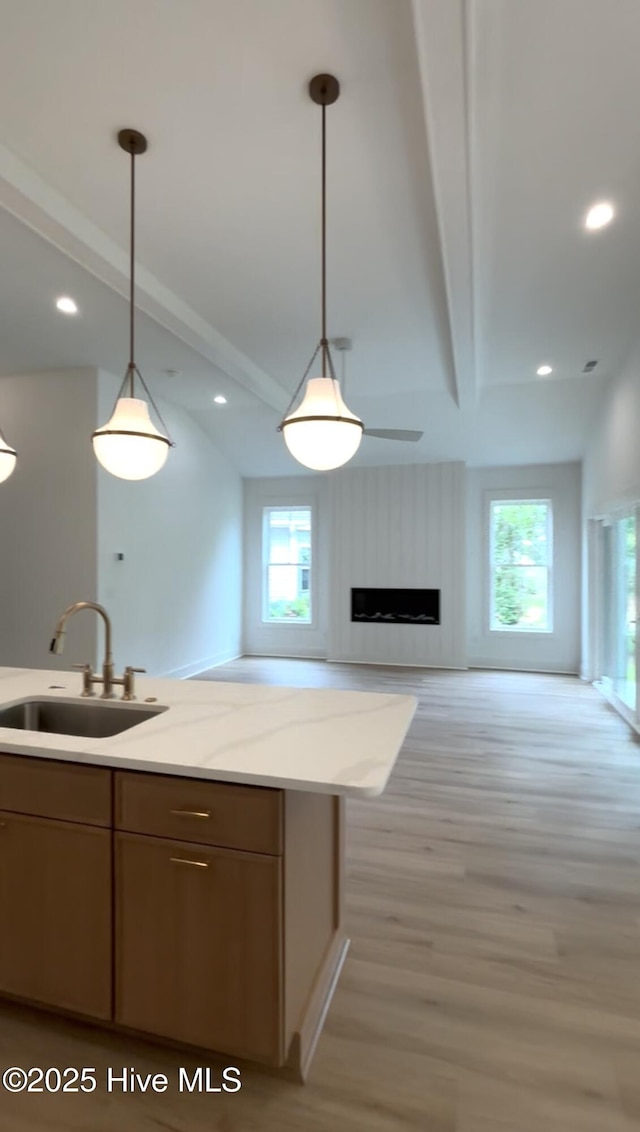 1643 Deerfield Dr SW, Ocean Isle Beach, NC 28469 - kitchen with light wood finished floors, decorative light fixtures, a fireplace, light stone countertops, and open floor plan
