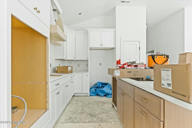 kitchen featuring white cabinets, vaulted ceiling, and custom exhaust hood