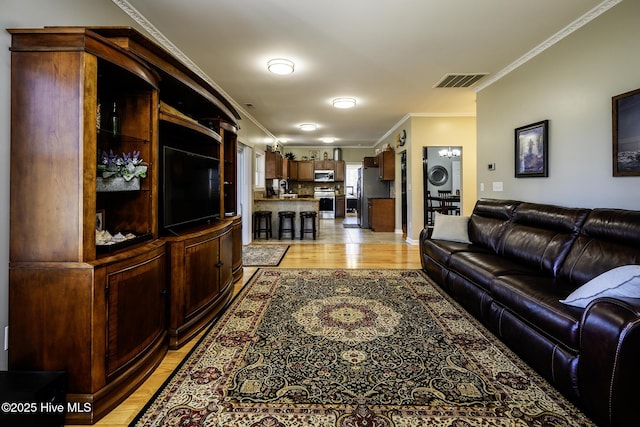 living area with ornamental molding, light wood finished floors, and visible vents