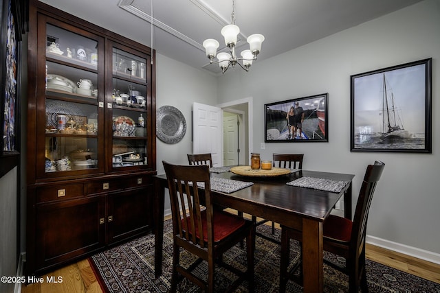 dining room featuring dark wood-style floors, baseboards, and a notable chandelier