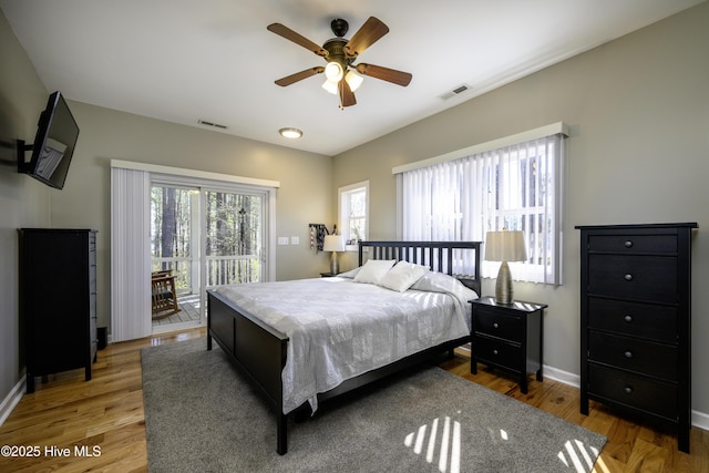 bedroom with baseboards, access to outside, visible vents, and wood finished floors