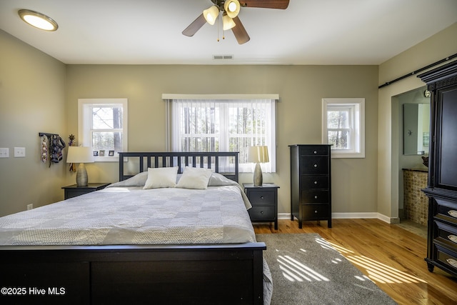 bedroom featuring a ceiling fan, baseboards, visible vents, and wood finished floors