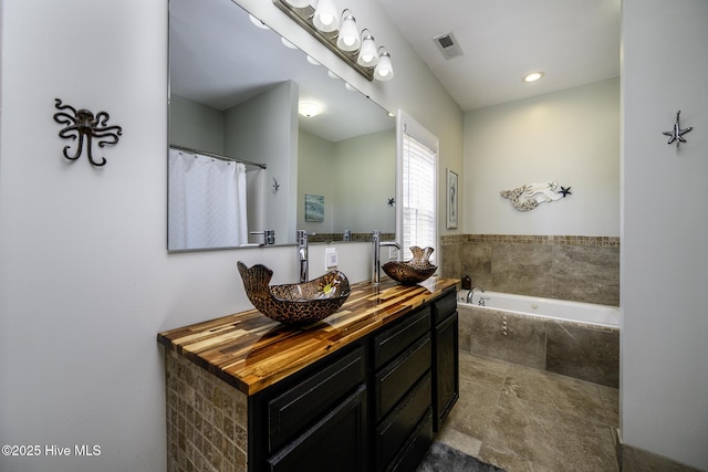 bathroom with a garden tub, visible vents, and vanity