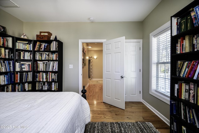 bedroom with visible vents, baseboards, and wood finished floors