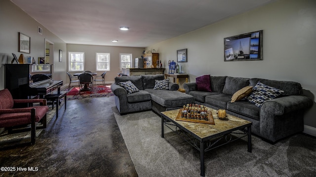 living room with finished concrete flooring, baseboards, and visible vents