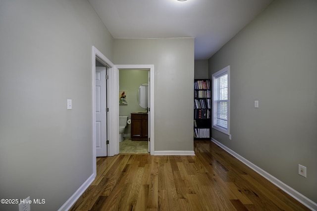 hallway featuring light wood-style flooring and baseboards