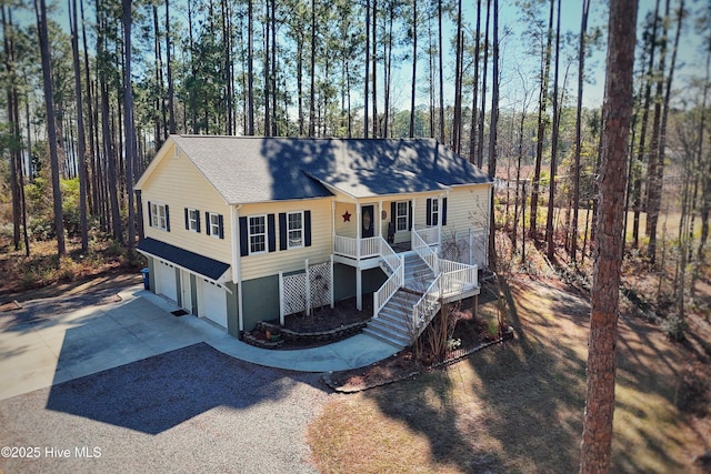 view of front facade featuring an attached garage, covered porch, driveway, stairway, and roof with shingles