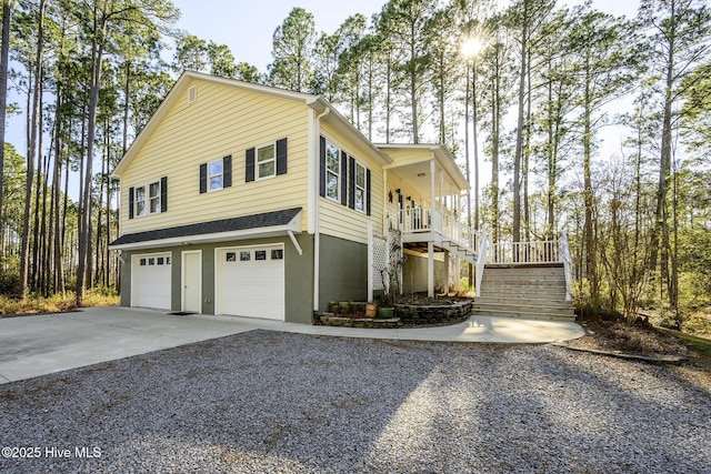 view of front facade featuring stucco siding, a porch, a garage, driveway, and stairs