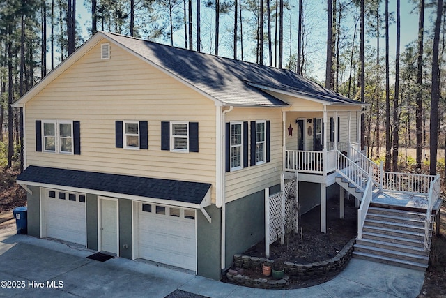 view of front of home with roof with shingles, a porch, concrete driveway, a garage, and stairs