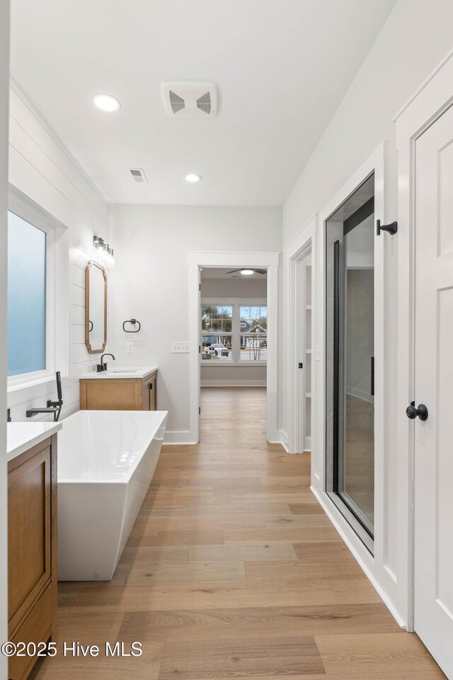 1773 Oakbrook Dr SW, Ocean Isle Beach, NC 28469 - bathroom featuring a freestanding tub, vanity, visible vents, recessed lighting, and wood finished floors
