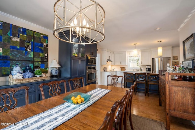 dining area featuring crown molding, an inviting chandelier, and wood finished floors