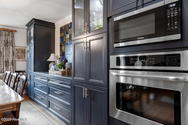 kitchen with glass insert cabinets, appliances with stainless steel finishes, and crown molding