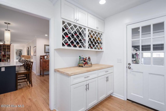 bar with a dry bar, light wood finished floors, baseboards, and recessed lighting