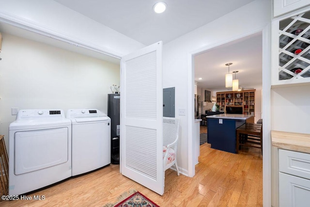 washroom featuring light wood-style flooring, laundry area, electric panel, and washer and clothes dryer