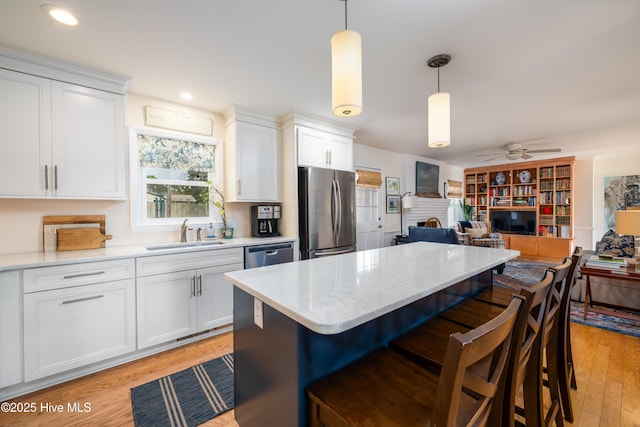 kitchen with stainless steel appliances, a breakfast bar, a fireplace, a kitchen island, and a sink