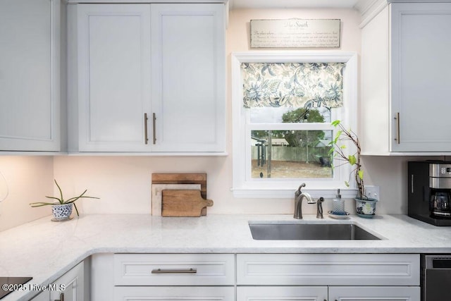 kitchen featuring dishwasher, light stone counters, a sink, and white cabinetry