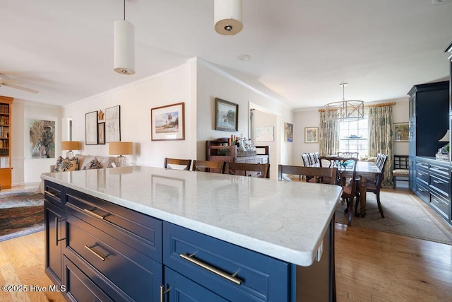 kitchen with open floor plan, hanging light fixtures, crown molding, light wood-type flooring, and blue cabinetry