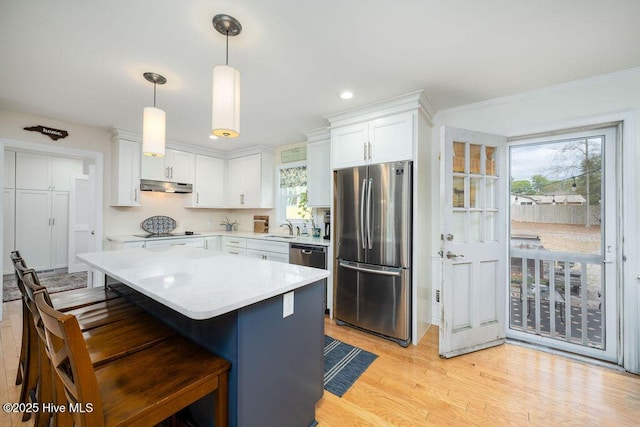 kitchen with under cabinet range hood, stainless steel appliances, a sink, white cabinetry, and light countertops