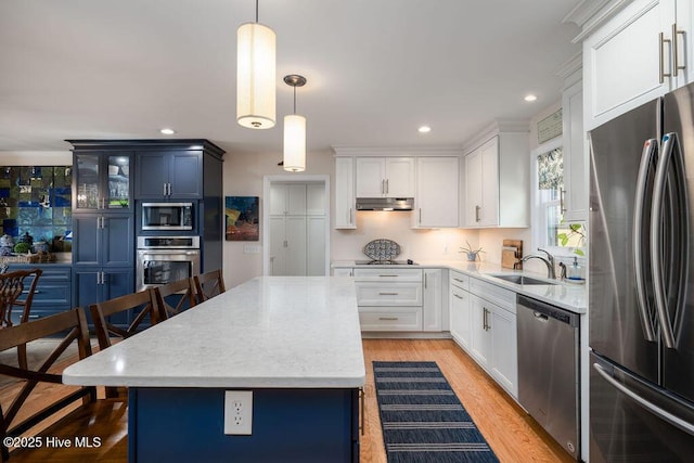 kitchen featuring stainless steel appliances, light stone counters, a sink, and under cabinet range hood