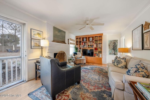 living area with ceiling fan, a fireplace, ornamental molding, and wood finished floors