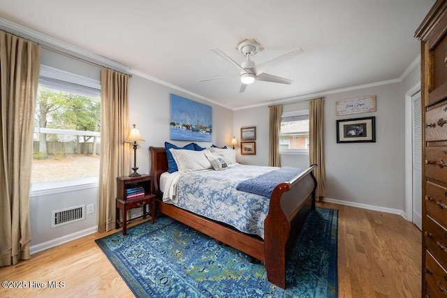 bedroom featuring baseboards, light wood-style flooring, visible vents, and crown molding