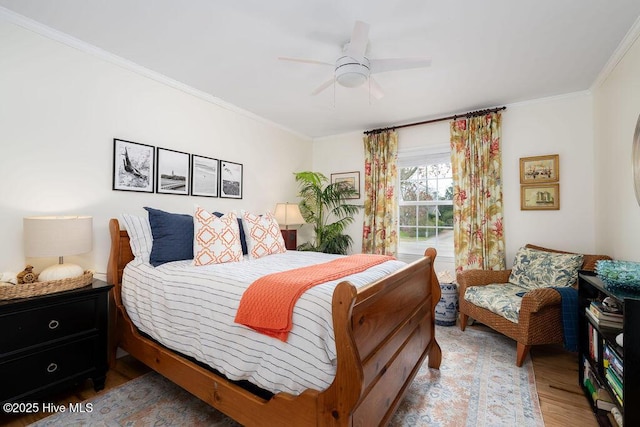 bedroom featuring ornamental molding, light wood finished floors, and a ceiling fan