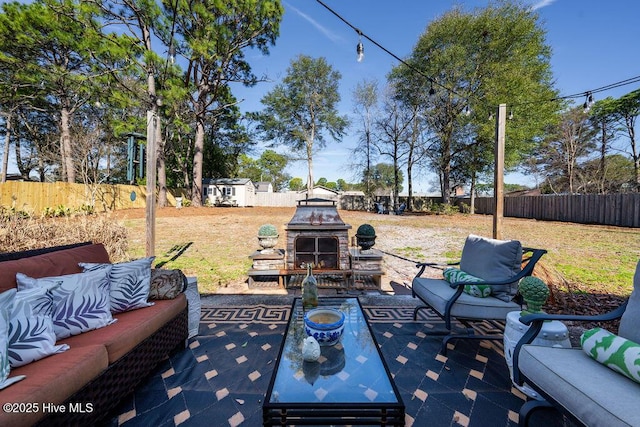 view of patio / terrace with an outbuilding, an outdoor living space with a fireplace, and a fenced backyard